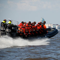 En RIB-båt med en grupp människor åker fram på mälaren med Skrapan i bakgrunden. Foto: Pressbild