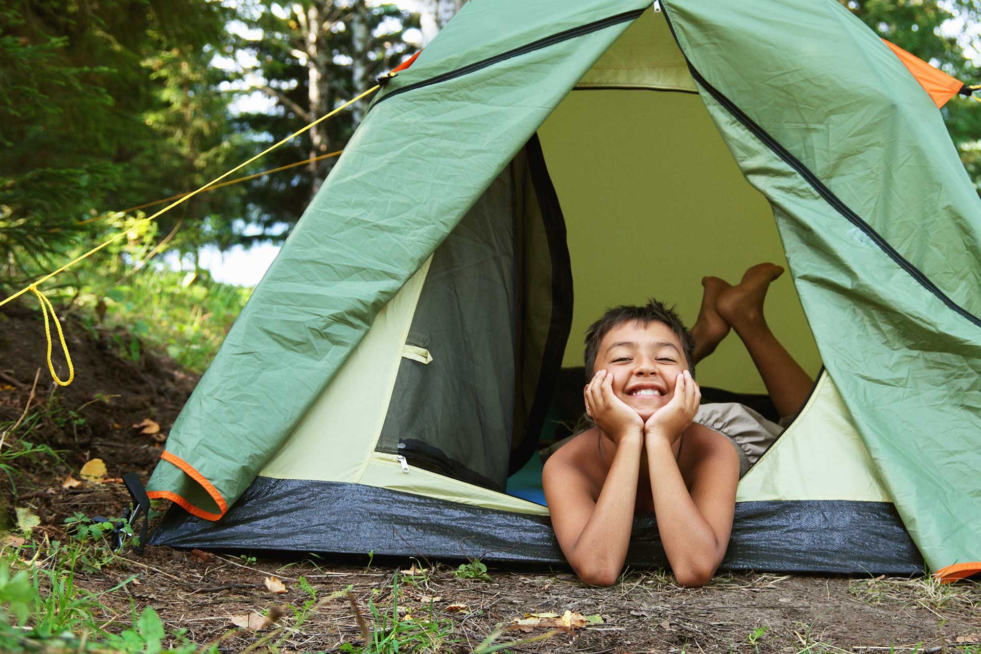Ett glatt barn i tält på camping. Foto: Mostphotos