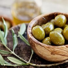 En träskål med gröna oliver och en olivkvist som symboliserar restaurangen Grekiska Grill och Bar. Foto: Pressbild