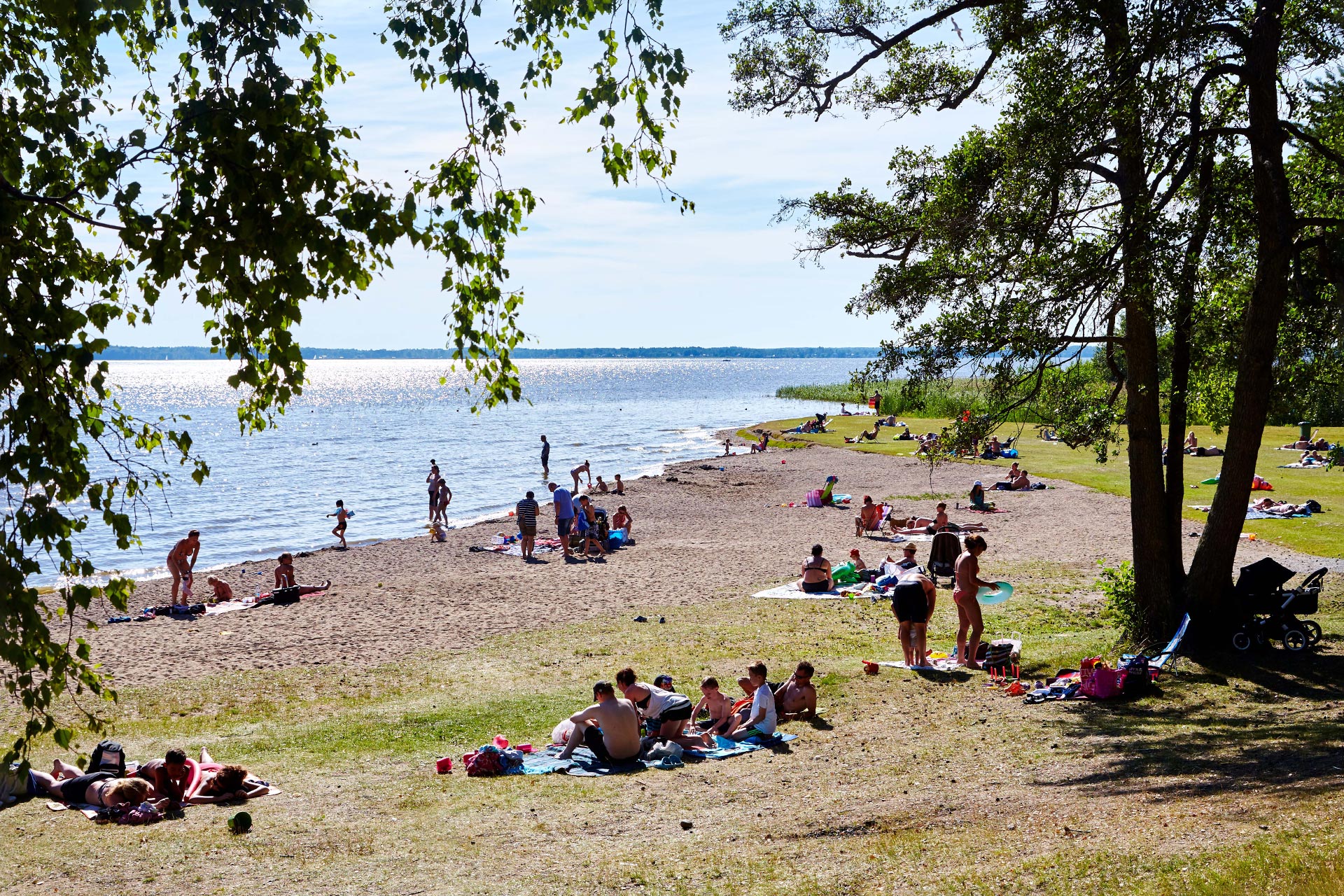 Vy över badstranden på Björnö med besökare som badar och solar. Fotograf: Pia Nordlander