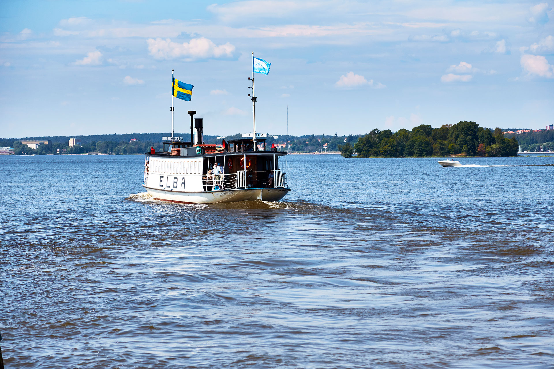 Elbafärgan åker runt på Mälaren med svenska flaggan och Rederi Mälardalens flagga som svajar. Fotograf: Pia Nordlander