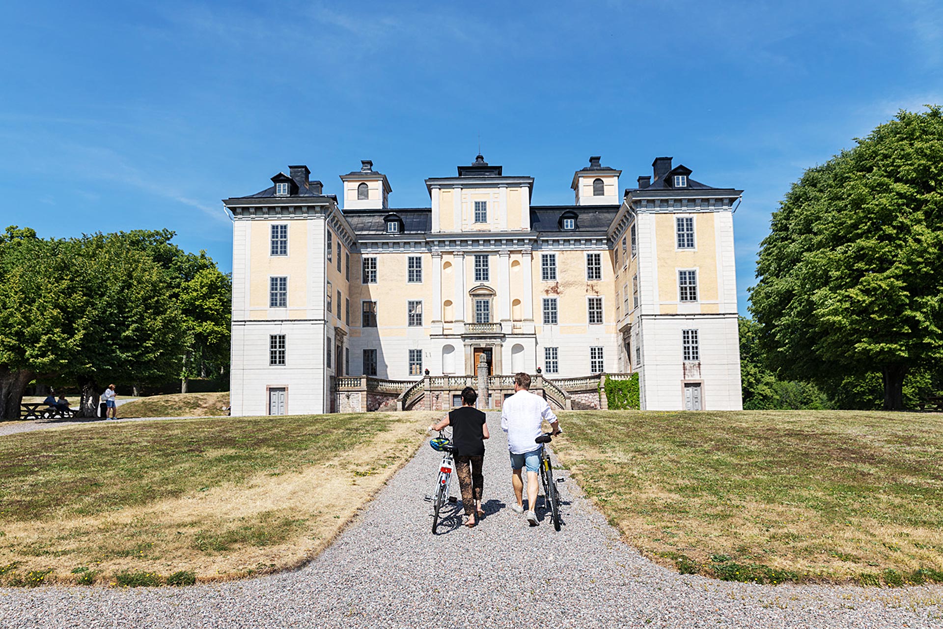 Två personer med cyklar går mot Mälsåkers Slott. Foto: Ulf Huett