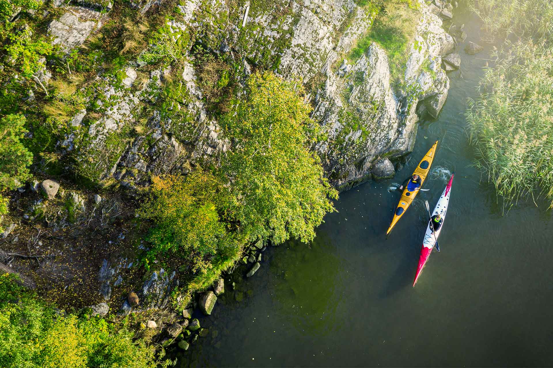 Vy ner från en klippa på två personer som paddlar kajak. Foto: Jonas Bilberg.